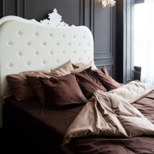 Close up view of bed with beaige linen and burgundy pillows close up