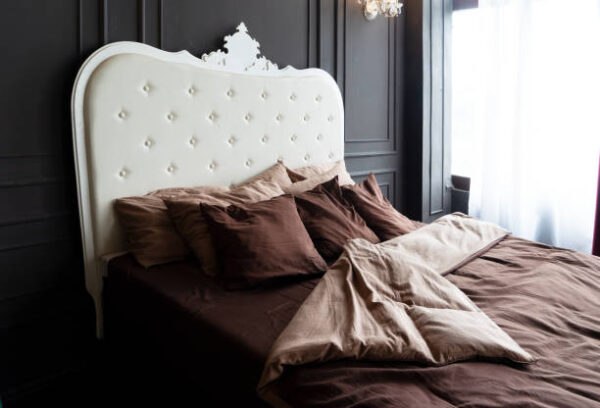 Close up view of bed with beaige linen and burgundy pillows close up