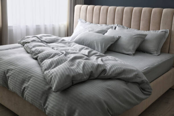 Comfortable bed with soft blanket and pillows indoors
