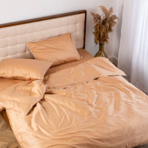 Peach cotton pillow and sheet bed linen messy top view