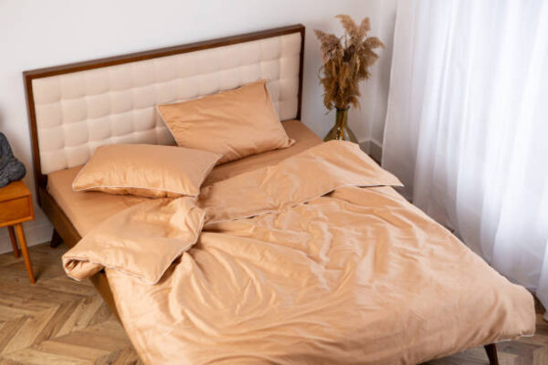 Peach cotton pillow and sheet bed linen messy top view
